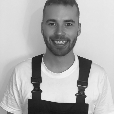 Primgaard team member Fred Primgaard (owner) smiling in branded overalls against light background